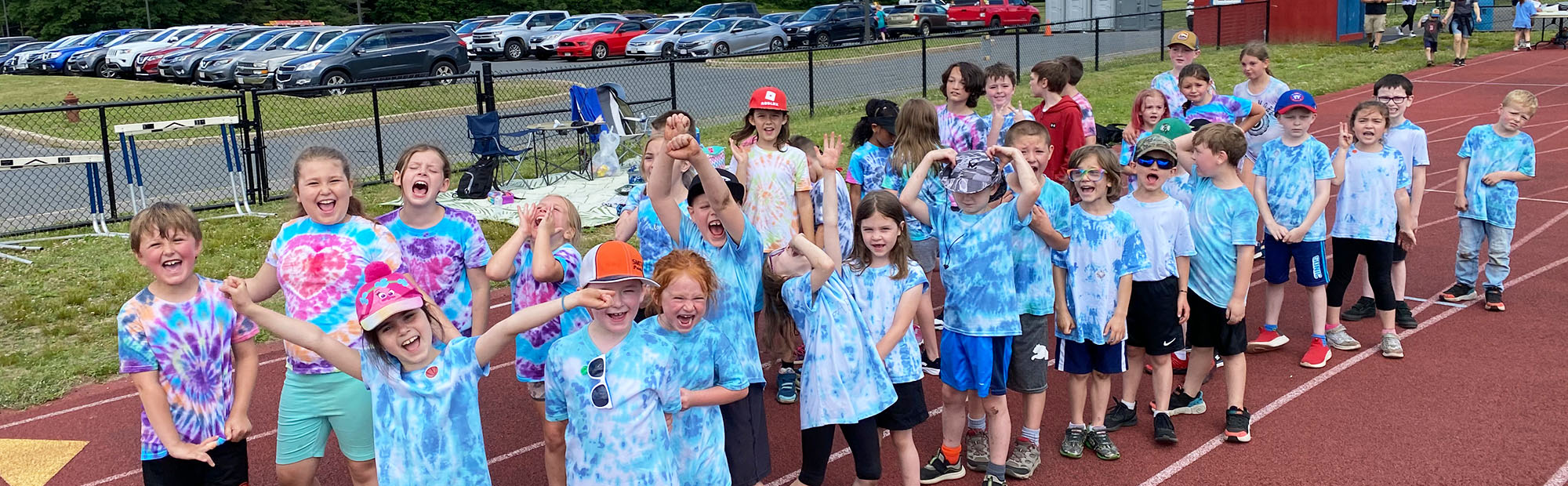 Group of happy elementary students wearing tie dye tees on the school track