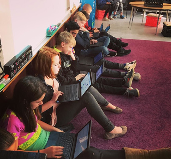 students using laptops on the floor